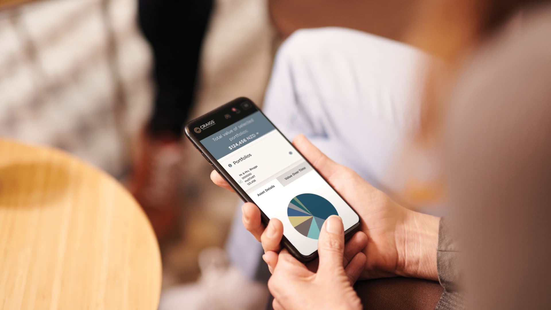 An individual holding her phone that shows a pie chart. The chart presents her family trust's portfolio.