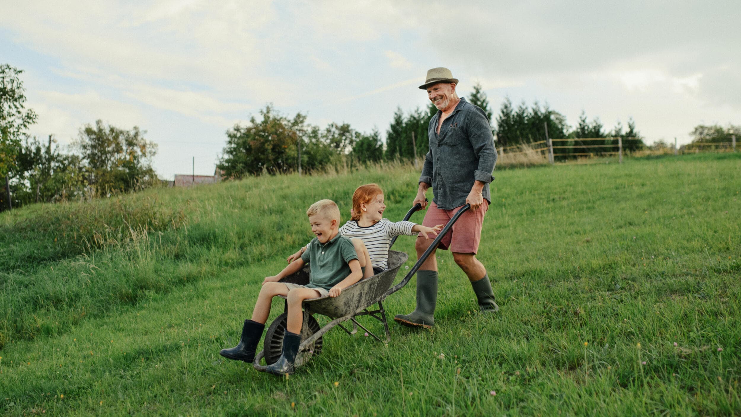 A grandad wheeling his grandchildren around his sustainable farm.